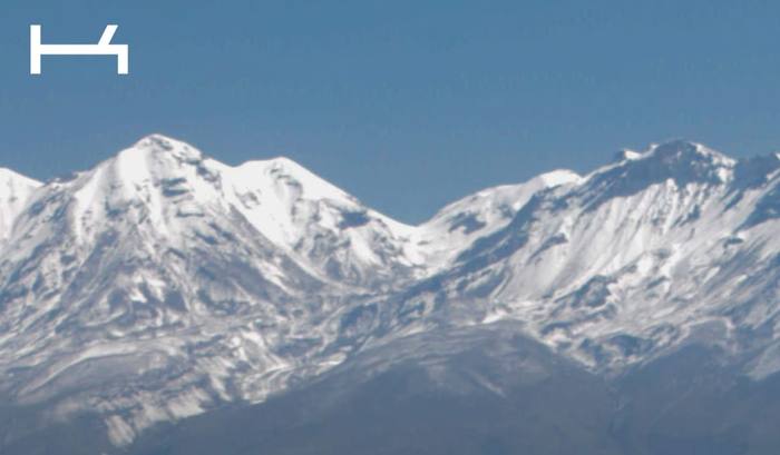 Cordillera nevada sobre campos verdes